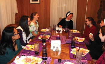 La Hermana Colleen (a la cabecera de la mesa) comiendo con participantes durante un retiro de discernimiento.