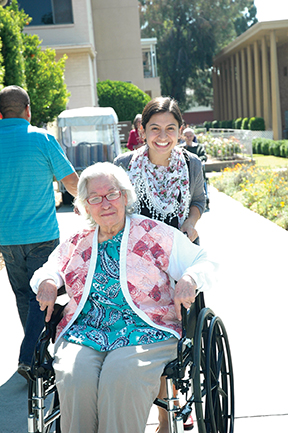 “Serving with Sisters” lay volunteer Cecilia Cuesta assists a woman in a wheelchair at Santa Teresita Medical Center in Duarte, CA.