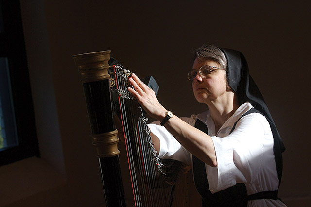 Sister Kathleen O’Neill, O.C.S.O. tunes her harp.