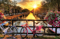 Bicycles parked in front of a canal with the sunset in the background